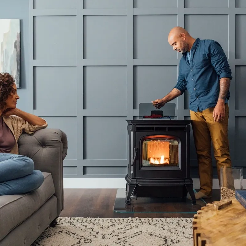 Couple relaxing in their living room beside a Harman pellet stove